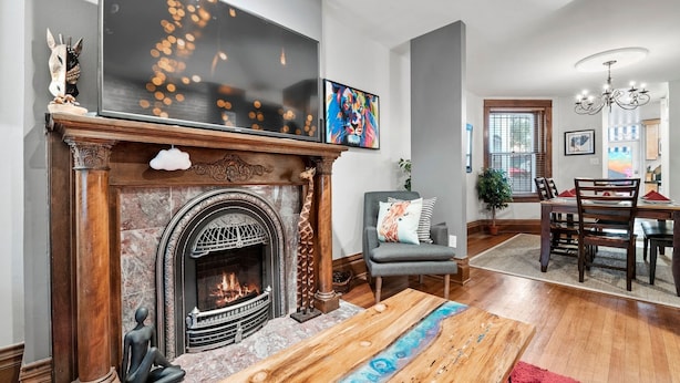A living room with a fireplace, a dining area, and a large window. - The Arusha House Capitol: Hill : Garage : Yard (Denver)