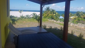 A covered outdoor area with a view of the ocean and palm trees. - COZY COTTAGE + NETFLIX + WIFI + JACCUZZI + PARKING (Sainte rose)