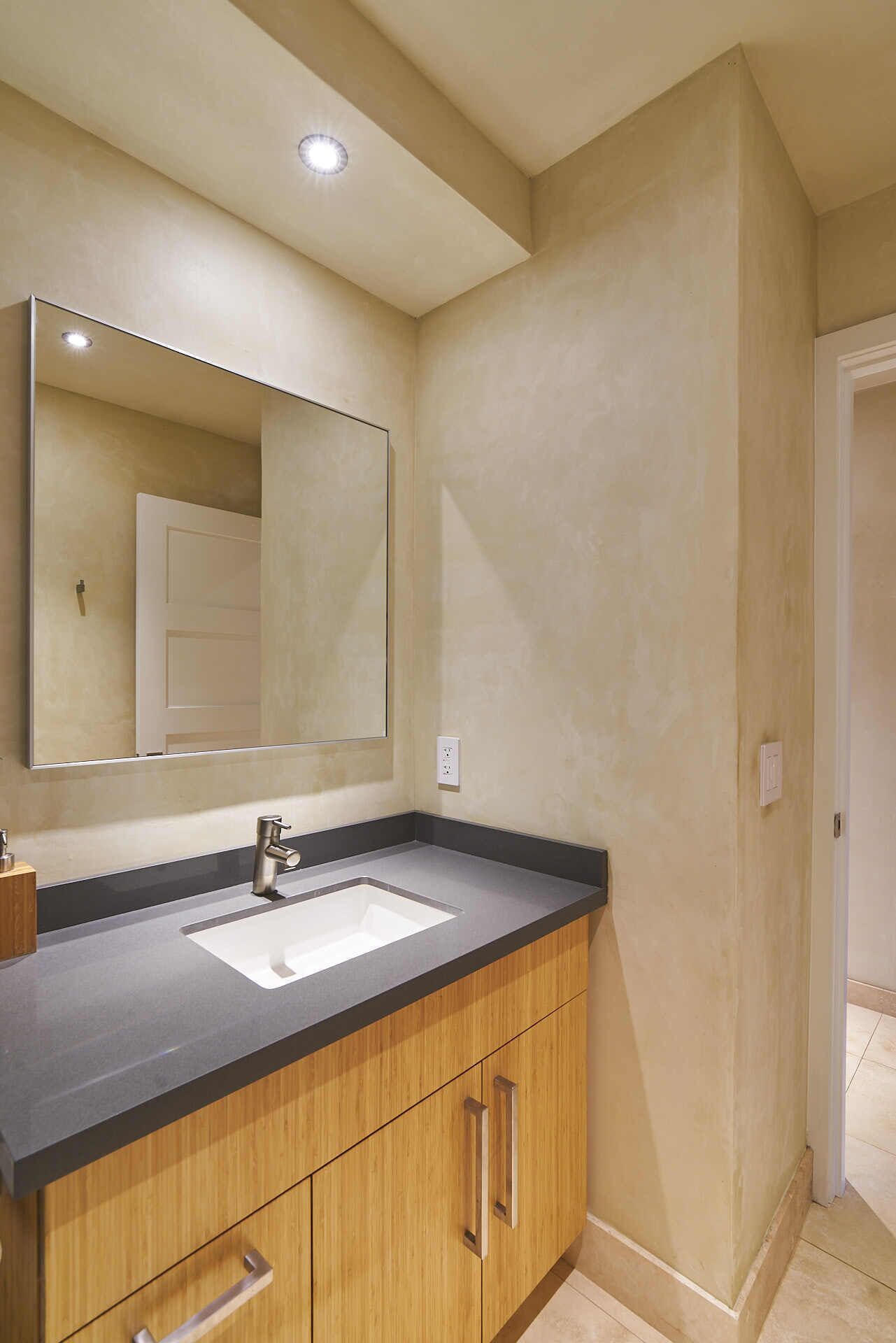Un baño con lavamanos doble, armarios de madera, un espejo grande y una lámpara en el techo.