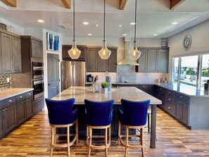 Una cocina moderna con una isla central, armarios de madera oscura, electrodomésticos de acero inoxidable e iluminación colgante.