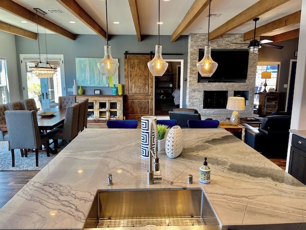 A modern kitchen with a marble island, built-in appliances, and pendant lighting.