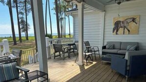 A covered outdoor area with a wooden deck, seating, and a painting of a horse.