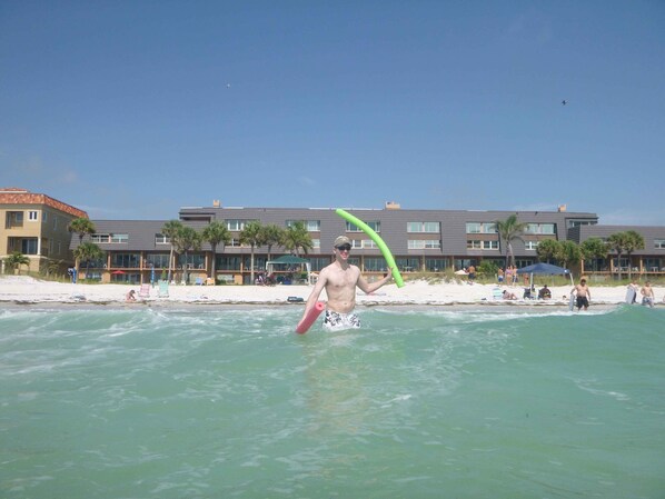 Un hôtel avec vue sur la plage, plusieurs étages et un espace piscine.