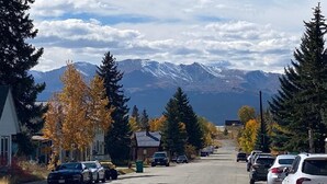 Une rue bordée de voitures garées, de maisons et, au loin, une chaîne de montagnes.