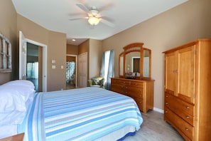 A bedroom with a bed, a wooden dresser, a mirror, and a ceiling fan. - Only 75 yards to the beach!!   (Tybee Island)