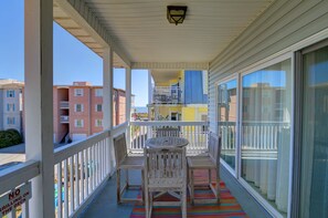 Un balcon avec des balustrades blanches, une table en bois et deux chaises.