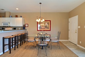 A dining area with a round table and chairs, a kitchen with white cabinets, and a hanging light fixture. - Only 75 yards to the beach!!   (Tybee Island)
