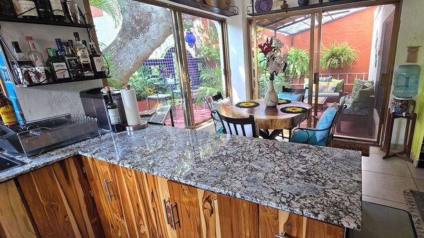 A kitchen with a granite countertop, wooden cabinets, and a dining area with a table and chairs.