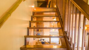 A wooden staircase with a handrail, leading to a room with a bed and a nightstand.