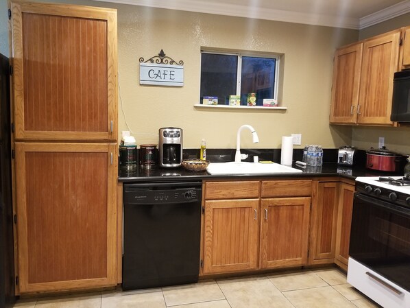 A kitchen with wooden cabinets, a coffee maker, a sink, and a stove.