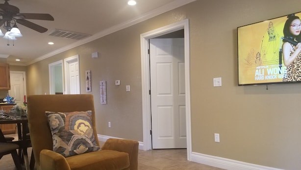 A living room with a brown armchair, a dining table with chairs, and a TV mounted on the wall. - CLOSE TO STRIP Very Private, GATED, Huge Open Floor Plan, WIFI, WASHER & DRYER (Las Vegas)