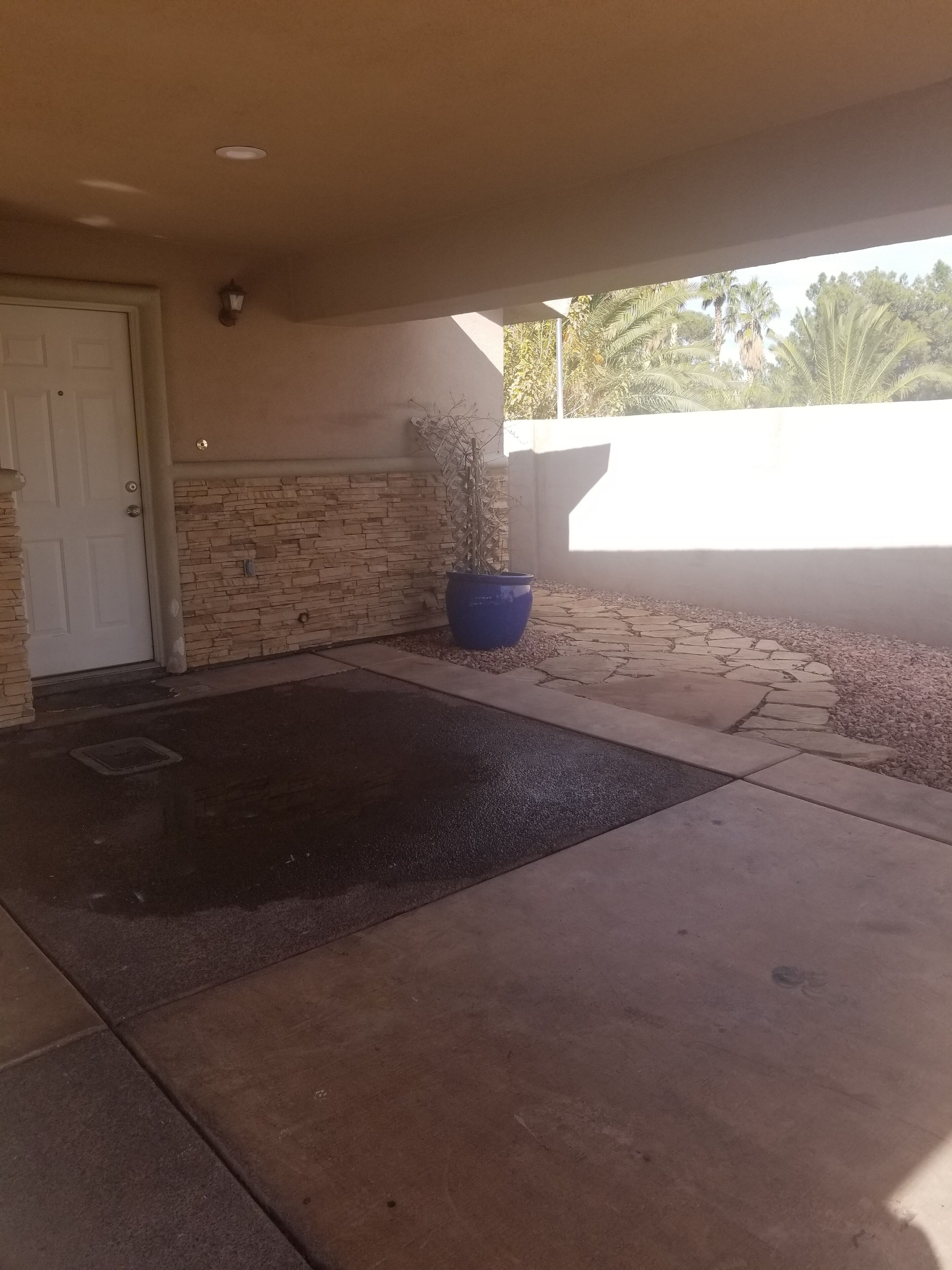 A covered entryway with a stone wall, a potted plant, and a doormat.