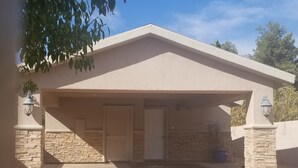 A single-story house with a covered garage, stone walls, and a door with a shutter. - CLOSE TO STRIP Very Private, GATED, Huge Open Floor Plan, WIFI, WASHER & DRYER (Las Vegas)