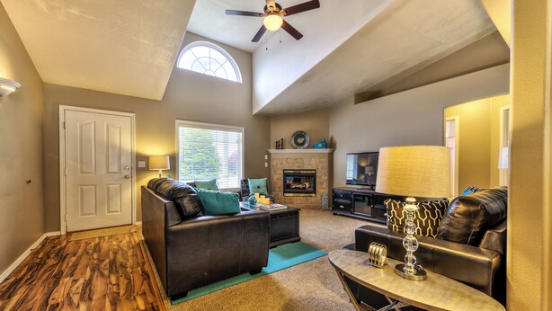 A spacious living room with a fireplace, leather sofas, and a ceiling fan. - GOLF COURSE, 4 Bdrm Single Level w/Garage!!! (Meridian)