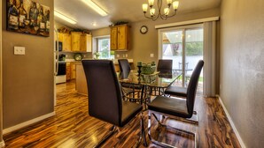 A dining area with a glass table and chairs, wooden flooring, a chandelier, and a view of the outdoors. - GOLF COURSE, 4 Bdrm Single Level w/Garage!!! (Meridian)