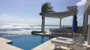 A pool with a view of the ocean, lounge chairs, and a covered seating area. - Early Holiday Booking Discount! (Tulum)