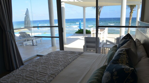 A bedroom with a large window overlooking a beach and ocean. - Early Holiday Booking Discount! (Tulum)