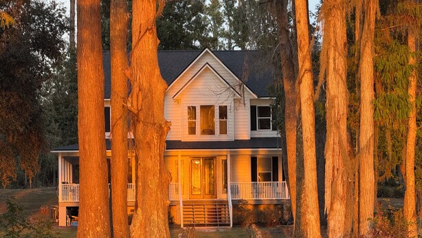 A two-story house with a porch, surrounded by tall trees. - Lakefront Southern Charm with private dock (Pinetta)