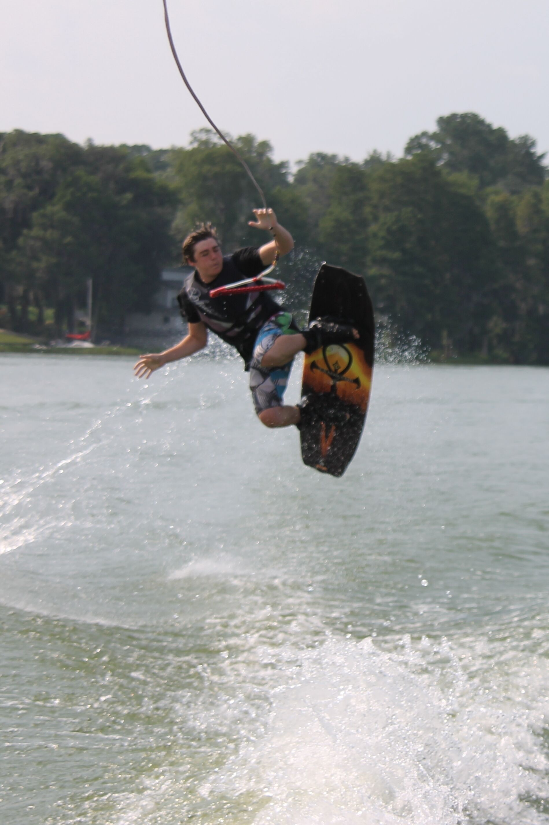 A person wakeboarding on a body of water with trees in the background.