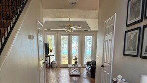 A spacious hallway with hardwood floors, a ceiling fan, and a view through glass doors to an outdoor area. - Lakefront Southern Charm with private dock (Pinetta)