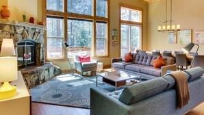 A spacious living room with a stone fireplace, large windows, a sofa set, and a dining area. - Tahoe Donner modern: Perfect for 3 families! 3 King/6 Twin. 4 BA, Cook's Kitchen (Truckee)