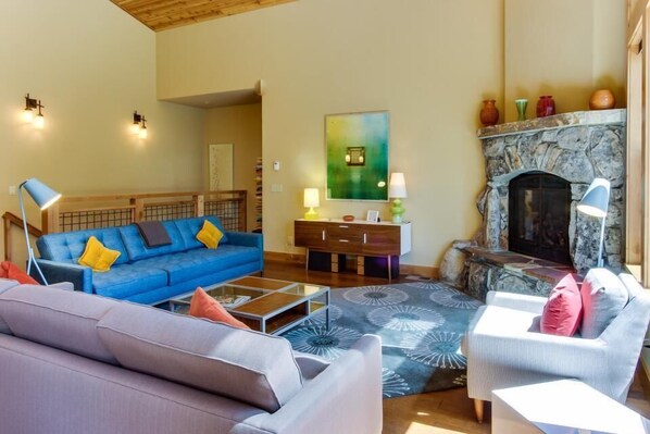 A living room with a blue sofa, a grey sofa, a fireplace, and a stone mantle. - Tahoe Donner modern: Perfect for 3 families! 3 King/6 Twin. 4 BA, Cook's Kitchen (Truckee)