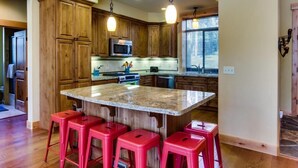 A kitchen with wooden cabinets, a granite island, red bar stools, and pendant lighting. - Tahoe Donner modern: Perfect for 3 families! 3 King/6 Twin. 4 BA, Cook's Kitchen (Truckee)