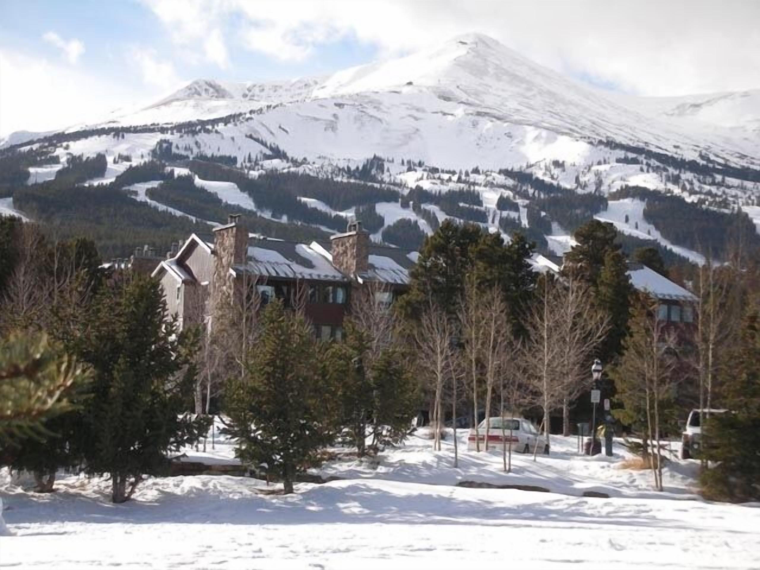 Une montagne enneigée, avec une station de ski en arrière-plan.