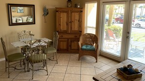 Un comedor con una mesa y sillas, una silla de mimbre, un armario y un cartel sobre la puerta.