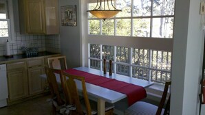 A kitchen with a dining area, wooden cabinets, a window with a view, and a hanging light fixture. - Best views on Sonoma Coast!Oceanfront,private hot tub, fire pit, pets considered (Bodega Bay)
