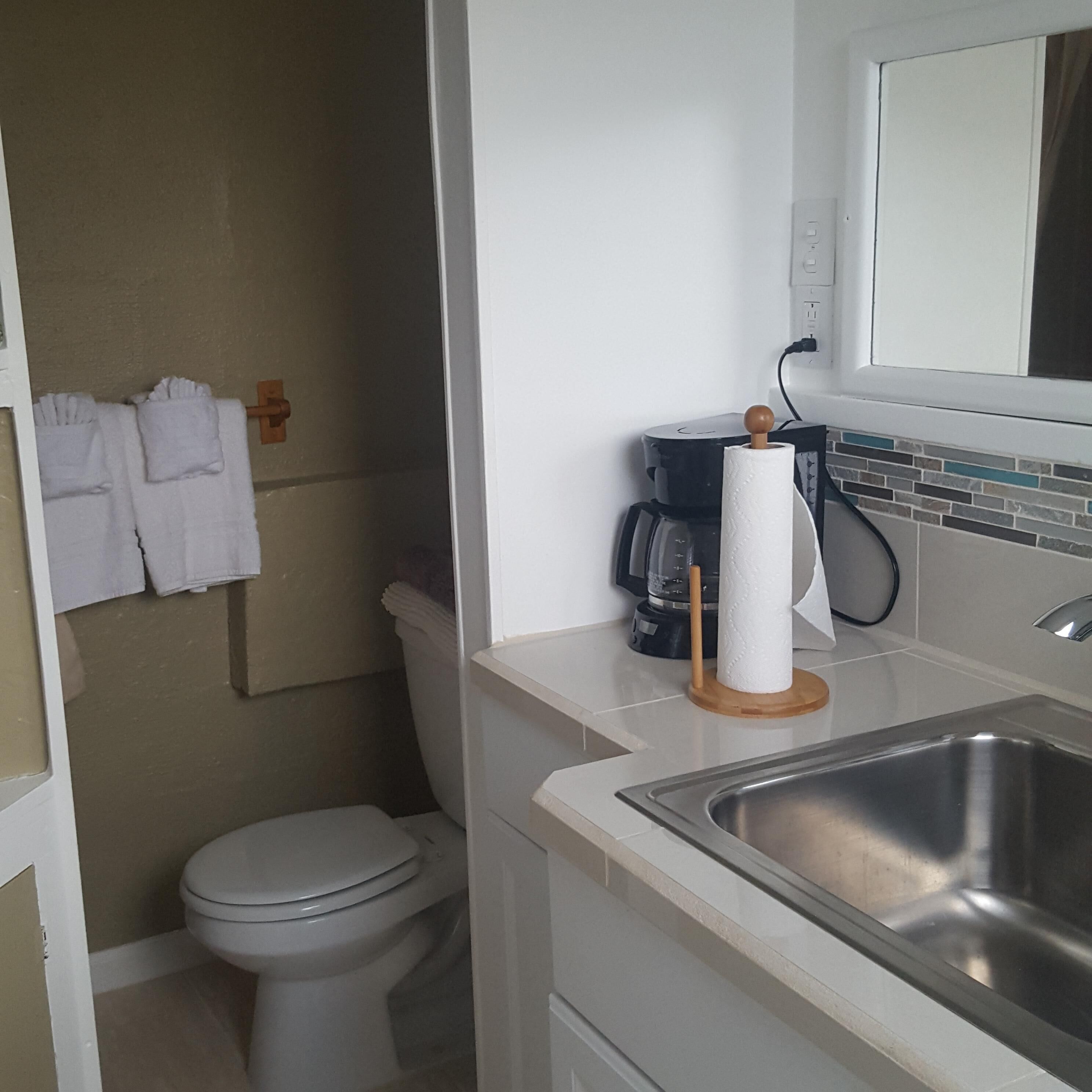 Une salle de bain équipée de toilettes, d’un lavabo et d’un porte-serviettes avec des serviettes blanches.