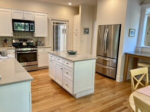 Una cocina moderna con armarios blancos, electrodomésticos de acero inoxidable y piso de madera.