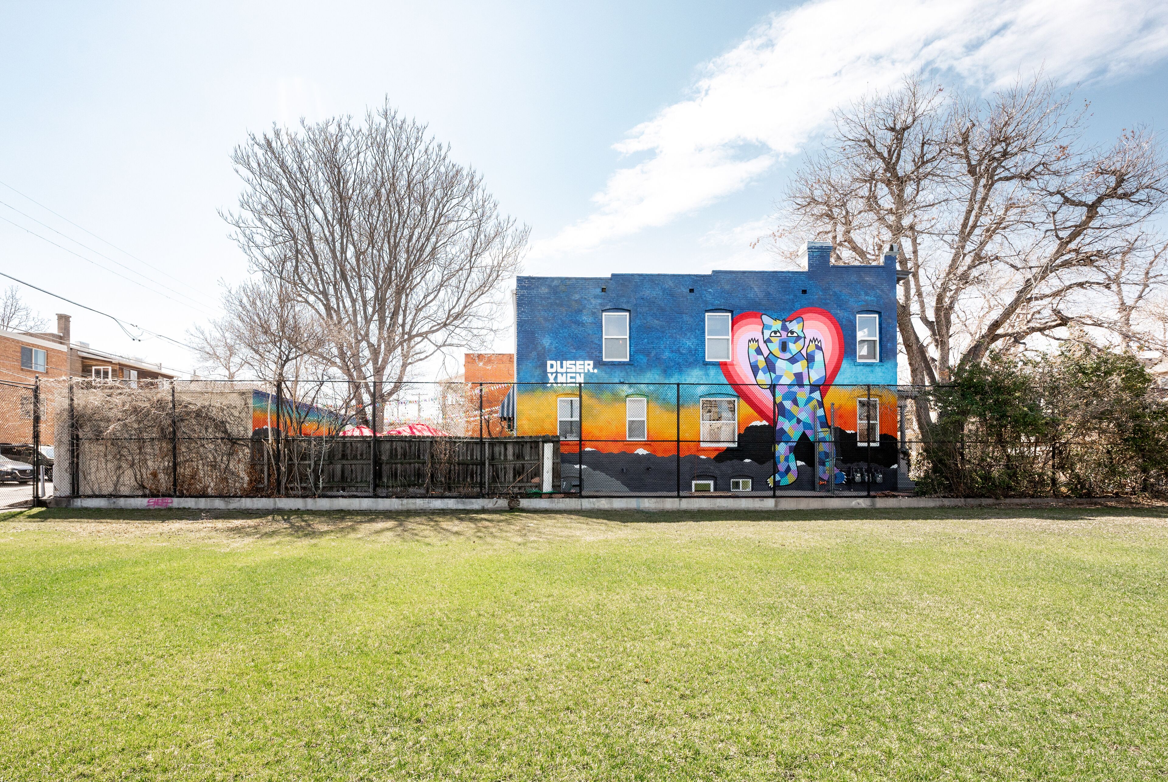 A building with a colorful mural on its side, featuring a heart and abstract patterns.