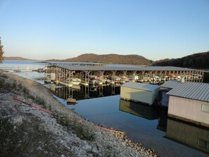 Moored boats line the marina, surrounded by a rocky shoreline and hills.