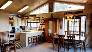 A cozy kitchen with wooden cabinets, a large island, and a dining area with wooden chairs.