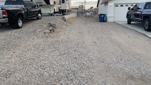 A gravel driveway with a black pickup truck and a white RV parked on the left.