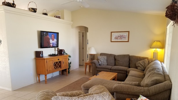A living room with a sofa, armchairs, a coffee table, a TV, and a lamp.