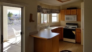 A kitchen with a central island, wooden cabinets, a microwave, and a stove.