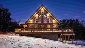 Un grand chalet lumineux, doté d’un toit triangulaire imposant et d’une terrasse couverte.