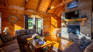 L’intérieur chaleureux d’un chalet en bois, avec une cheminée en pierre, des poutres apparentes et un coin salon confortable.