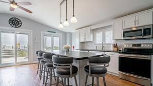 A kitchen with white cabinets, a stainless steel oven, and a bar area with stools. - Another Sunset by the Bay: Waterfront - 2-Bedroom (Leamington)