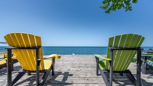 Two Adirondack chairs facing a wooden deck with a view of the ocean. - Another Sunset by the Bay: Waterfront - 2-Bedroom (Leamington)