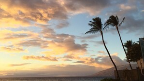 A beach scene with palm trees, a clear sky, and a few people walking along the shore.