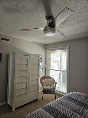 A bedroom with a ceiling fan, a window with blinds, a wardrobe, a chair, and a bed. - Lake Charlevoix condo in Landings At Boyne City (Boyne City)