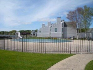 A residential area with a swimming pool, a fenced yard, and houses with a modern architectural style.