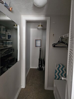 A narrow hallway with a closet on the left, a framed notice on the wall, and a radiator on the right. - Lake Charlevoix condo in Landings At Boyne City (Boyne City)