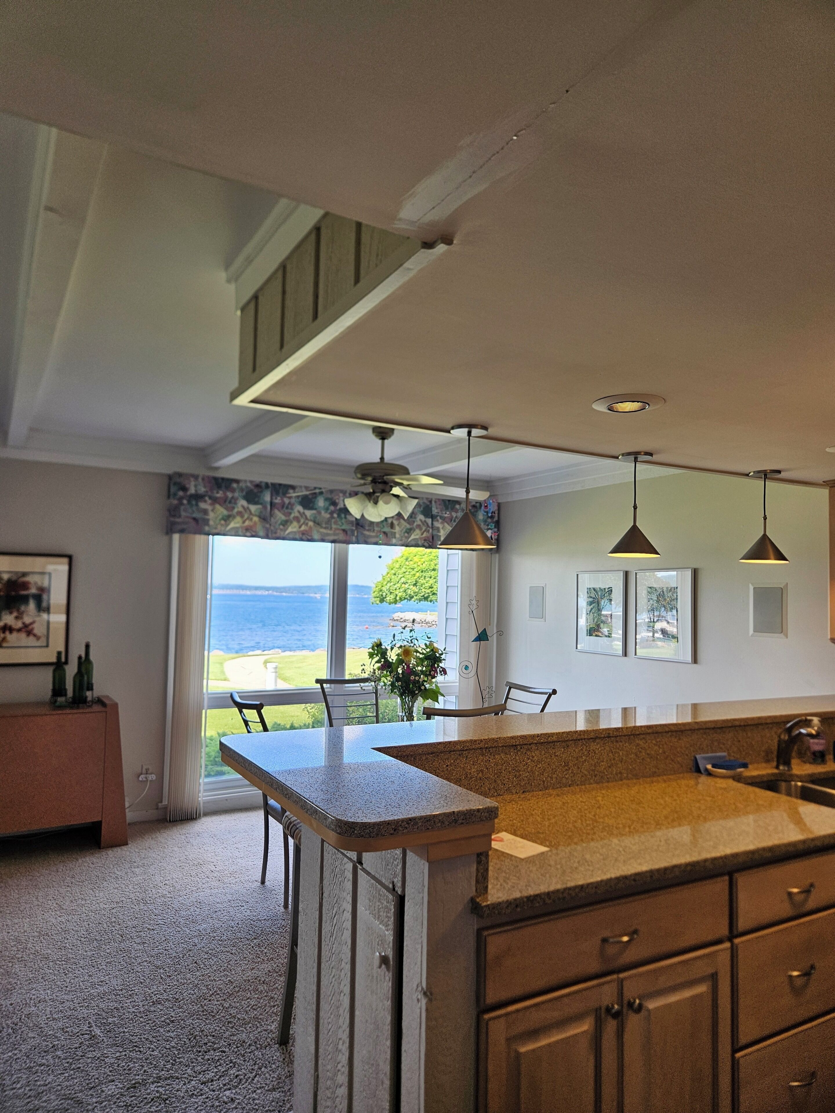 A kitchen with a large island, pendant lights, and a view of the outdoors.