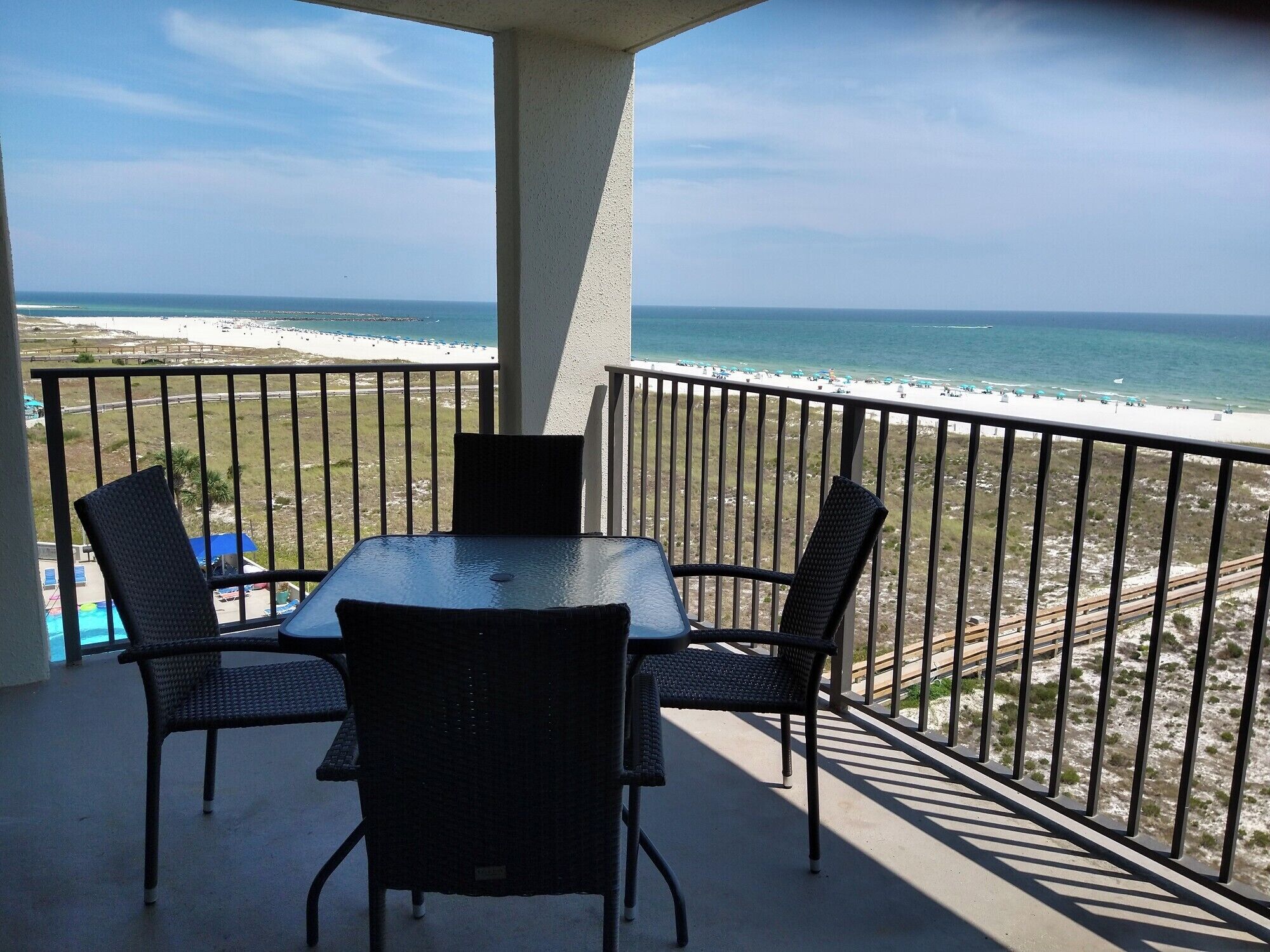 A balcony with a table and chairs overlooking a beach.