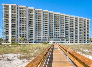 A multi-story hotel with a wooden boardwalk leading to the entrance.