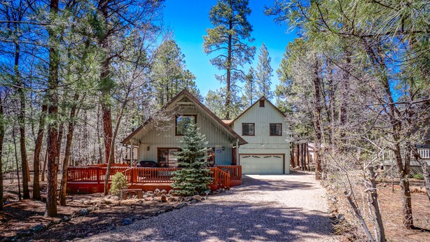 A cabin with a porch, surrounded by tall pine trees. - SPECTACULAR COZY CABIN NESTLED IN THE PINES BIG FRONT DECK FENCED FOR DOGS (PINETOP)
